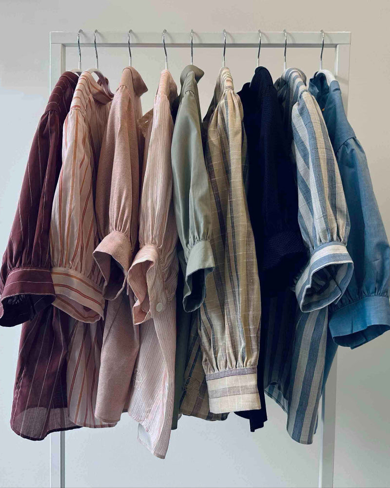 Collection of shirts on a rack against a plain background