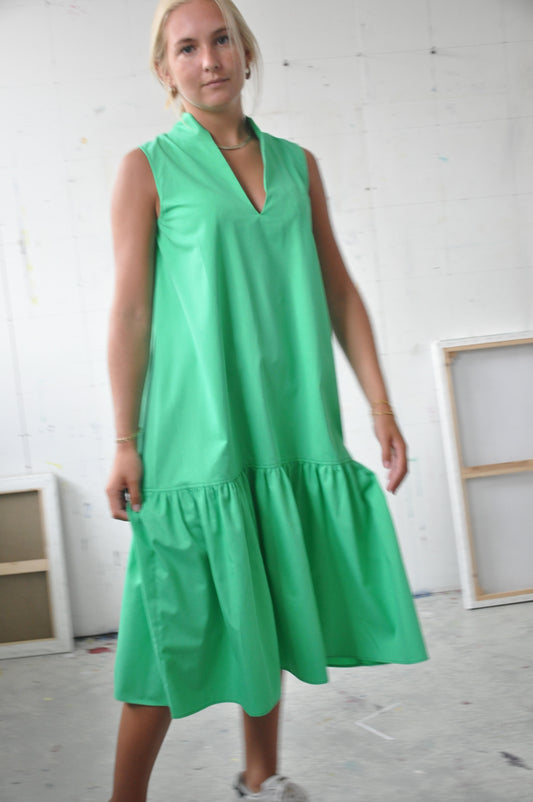 Green Sleeveless Dress With bold flounce at bottom. Neckline is made with graphic standing collar and a flattering V neck.
